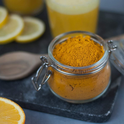 Kurkumapulver in Glas mit Orange und Zitrone